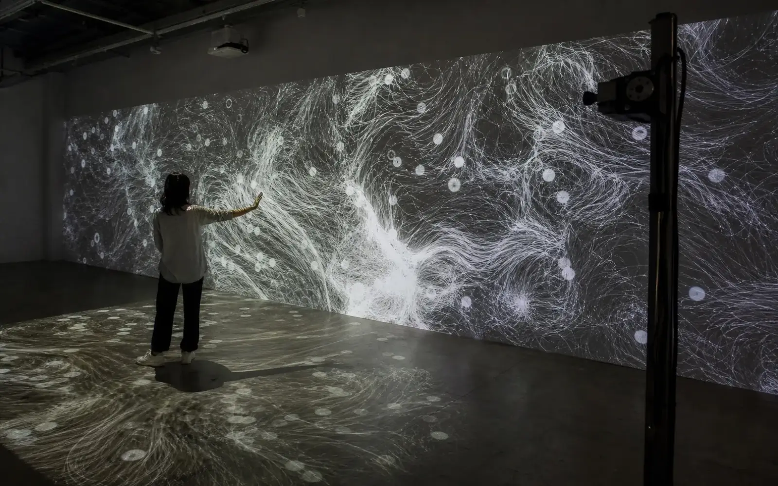 Visitor interacting with a generative projection installation across wall and floor