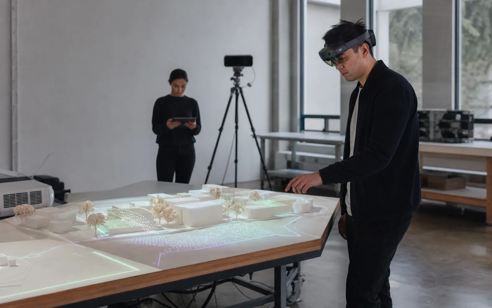 Designer in a mixed-reality headset exploring a projected architectural model on a large table